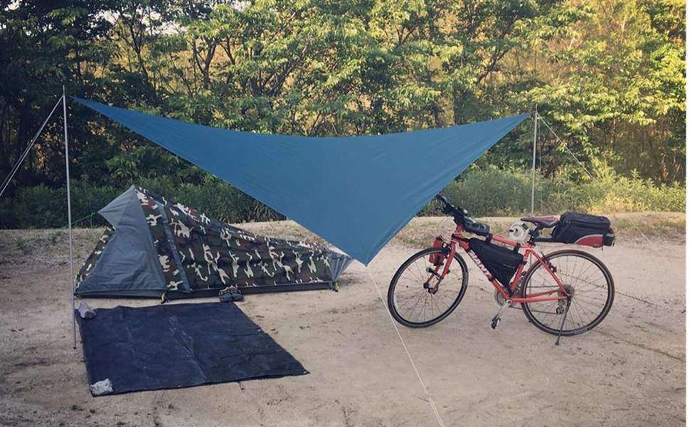 Geertop tent pitched under a blue tarp on sand, a bike with panniers beside it