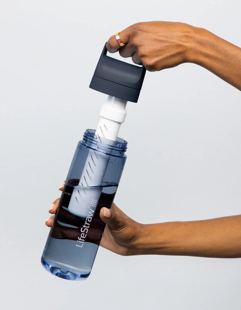 Hands lifting the lid with a white filter cartridge out of a LifeStraw Go bottle